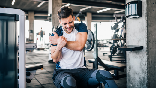 Man in gym with shoulder pain from impingement during exercise
